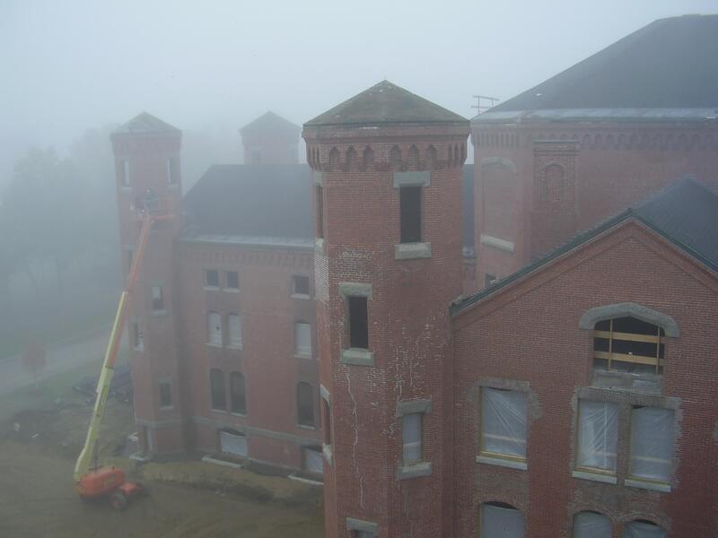 Roofing restoration on historical brick building in the fog